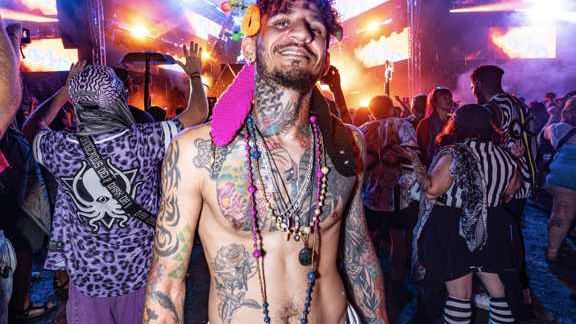 Festival portrait of a man at night with stage lights and crowd behind him