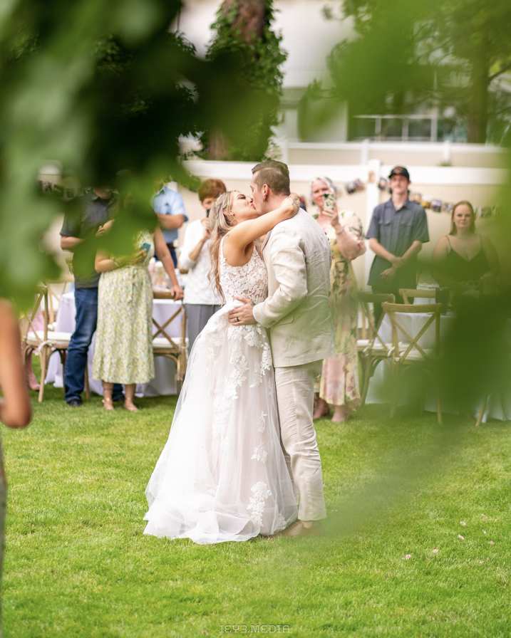 Bride and groom kissing at an outdoor wedding reception